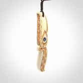 This picture shows a carved hawk in bone. It is a drop shaped pendant. The artist has carved traditional decorative kowhaiwhai designs into the body and these run up the sides of the hawk. These have specific meanings. It is provided with a hand-plaited brown cord that is length adjustable. Shipping is included and we ship worldwide.